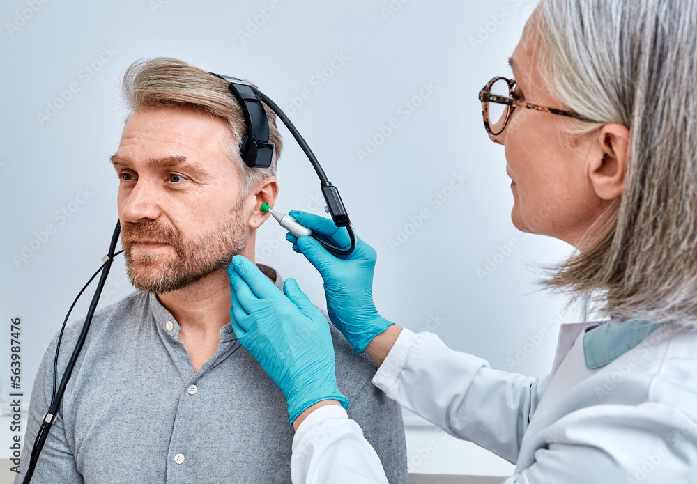 Experienced audiologist with tympanometer probe doing tympanometry