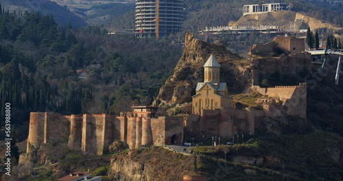 Church of St. Nicholas the Wonderworker on territory of Narikala fortress on the rocks of Sololak hill, wooded hills in background, cable car, Narikala fortress
