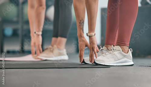 Fitness, hands or women stretching legs at gym to warm up body or relax muscles for workout exercise. Girls, focus or healthy sports people training together for support, inspiration or motivation