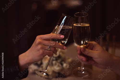 Two glasses with sparkling champagne wine in hands  concept for holiday  bokeh  in a restaurant. Romantic dinner. Man and woman are holding glasses of champagne. Concept for Valentine s day or date
