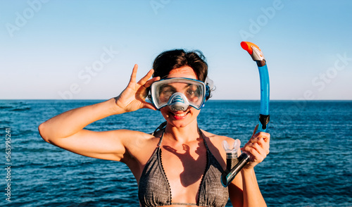 Young beautiful woman in diving mask on a tropical island.Female tourist having fun diving on sea background. Happy tourist enjoys snorkeling on vacation