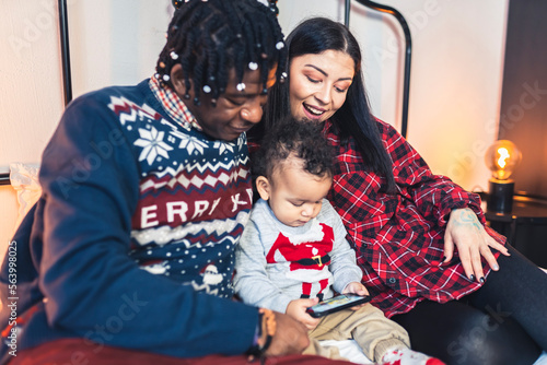 Multiracial parents with their toddler son playing games on the phone. High quality photo