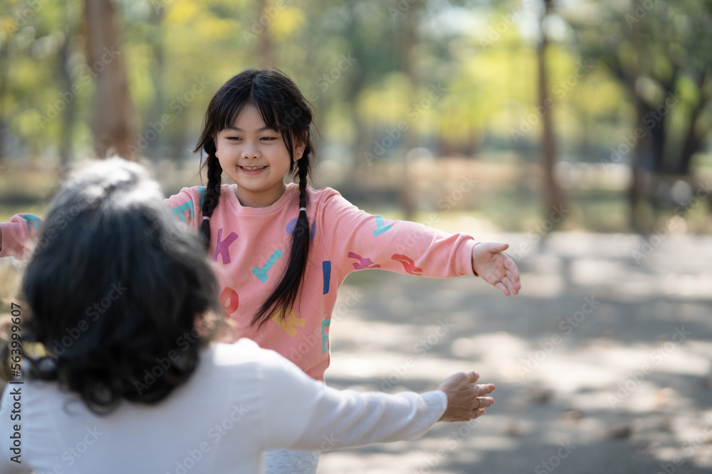 Happy young girl and her grandmother hugging in the public park, having a great itme Happy young girl and her grandmother hugging in the public park, having a great itme