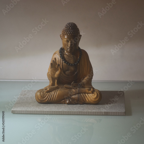 Sitzende Buddha Figur mit Kette auf Steinplatte no people