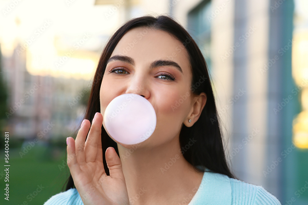Beautiful woman blowing gum near building outdoors Beautiful woman blowing gum near building outdoors