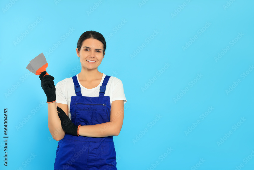 Professional worker with putty knives on light blue background, space for text Professional worker with putty knives on light blue background, space for text