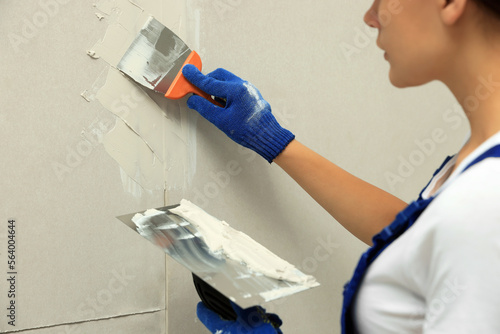 Professional worker plastering wall with putty knives, closeup