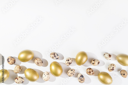 Eggs painted golden and quail eggs on white background. Minimal Easter concept. Natural farm products. Frame with place for text