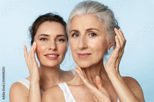 Two women of different ages and skin types take care of their facial skin, apply moisturizer, and look at the camera