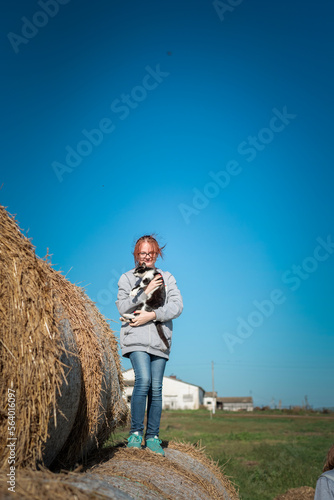 Young beautiful girl with a cat on straw bales.