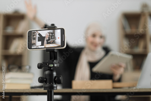 Focus on phone screen , muslim woman recording video on phone camera while unpacking box with new wireless tablet. Female influencer sharing with subscribers her positive feedback about new order.