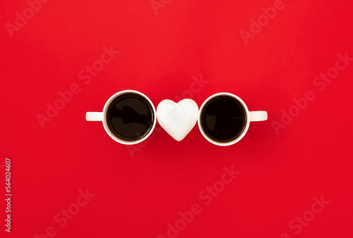 Two white coffee mugs with heart connecting in the form of sunglasses on bright red background. Banner or greeting card for Valentine's Day, Christmas or New Year, Women's day, date or other occasion.