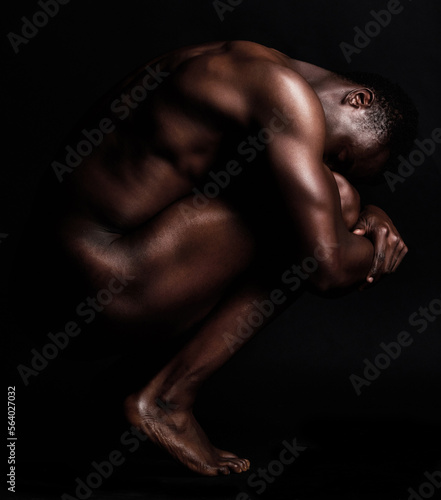 Nude, art and naked body of a strong black man in dark studio for sexy muscle and sexuality. Sport person or bodybuilder model for motivation, health and wellness in art deco form or shape background