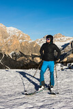  A young man, a happy skier, admires the Italian Dolomites mountains. Skiing, winter sports. Młody mężczyzna, szczęśliwy narciarz podziwia włoskie góry Dolomity. Narty, sporty zimowe.