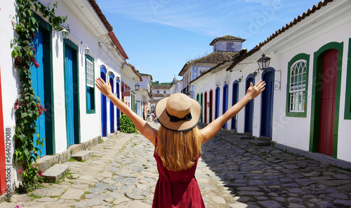 Joyful girl in Paraty, Brazil. Beautiful young woman with raised arms walking in colorful historic town of Paraty, UNESCO World Heritage Site, Brazil. photo