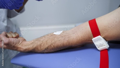 Male bare hand prepared for a blood test. Nurse in latex gloves inputs the needle of the syringe into patient’s vein. Close up. photo