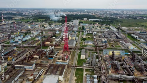Aerial view of chemistry plant with lots of pipes and smoking industial tower. Chemical plant  with big city in backgroun. Industrial pollution  