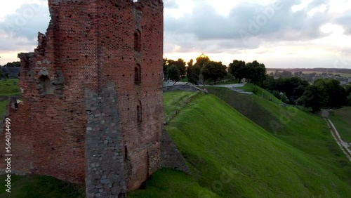 Drone aerial passing by ruined medieval castle tower in Navahrudak, Belarus on a green with stormy clouds in the background/