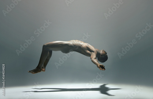 Float, man and naked model in a white background studio for creative art with shadow. Isolated, floating and nude body of a african male in the air with light showing artistic and erotic projection photo