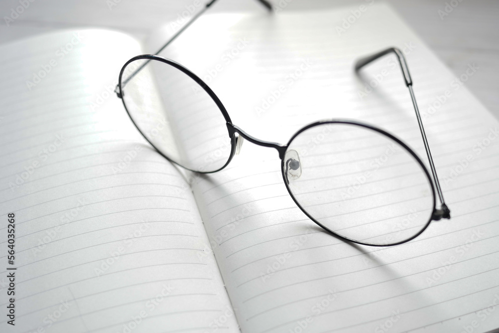 notepad, eyeglass and a pencil on wooden table notepad, eyeglass and a pencil on wooden table