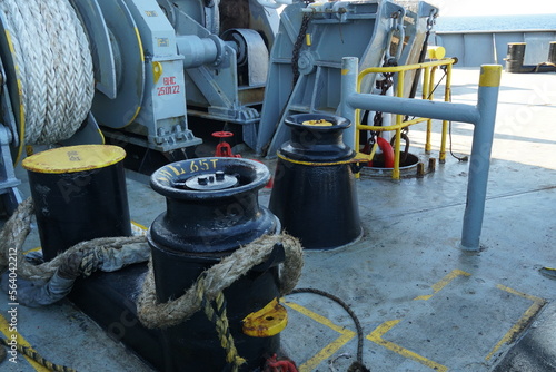 Fotografie View on yellow and black painted bollards and mooring roller in forward manoeuvring station on cargo container vessel