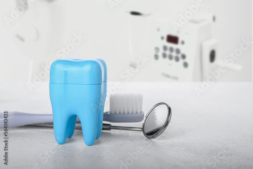 Plastic tooth with brush and dental mirror on table in clinic