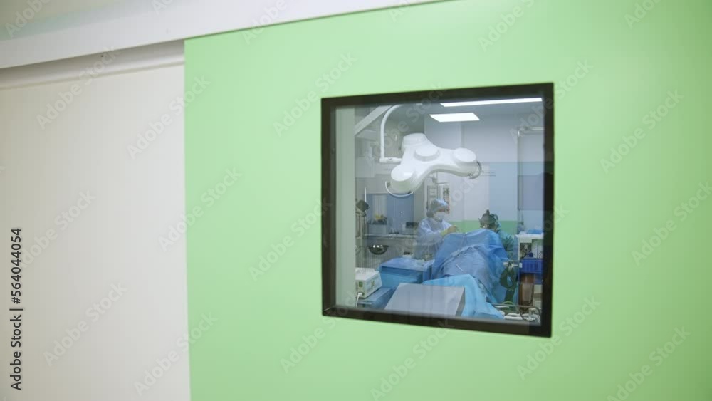 Closed doors to the surgery room in modern hospital. Medical professionals performing surgery inside the operational theatre. Closed doors to the surgery room in modern hospital. Medical professionals performing surgery inside the operational theatre.