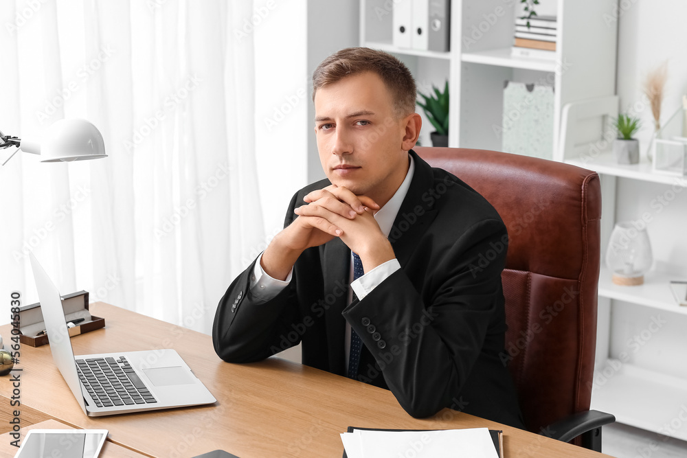 Handsome businessman sitting at desk in office Handsome businessman sitting at desk in office