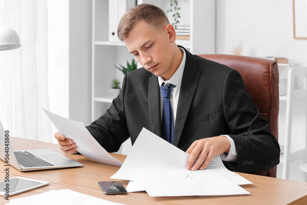 Handsome businessman working with papers at desk in office Handsome businessman working with papers at desk in office
