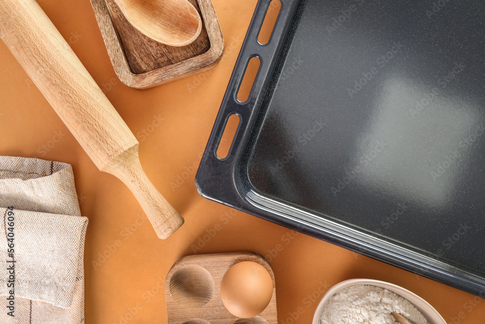 Baking tray with utensils on beige background, closeup Baking tray with utensils on beige background, closeup