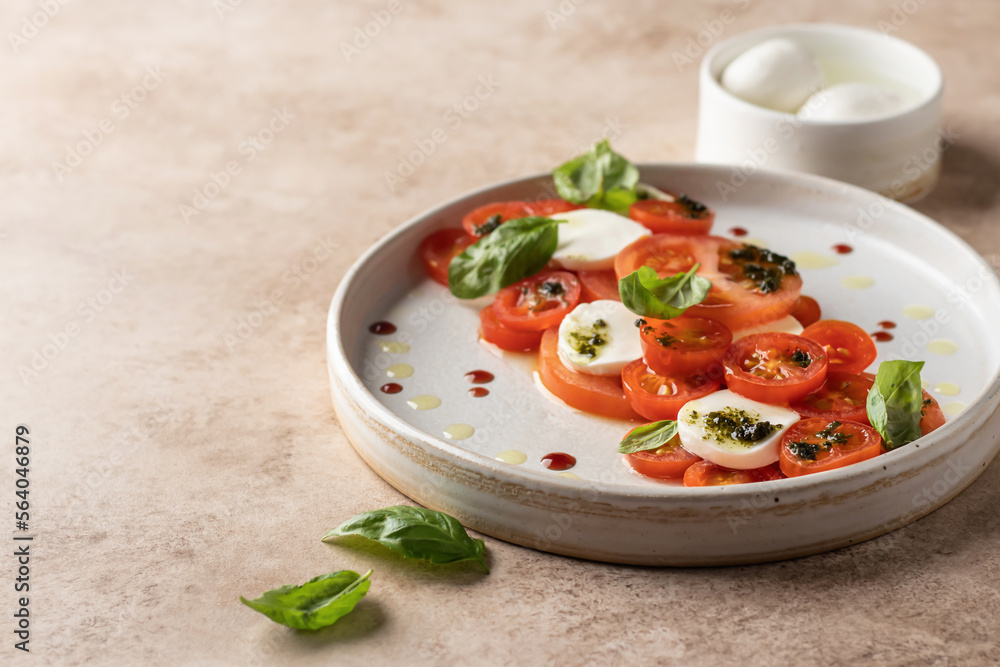 Caprese salad in modern linear feed with tomatoes, basil, mozzarella, pesto, balsamic sauce and olive oil. Traditional Italian food on beige background, copy space Caprese salad in modern linear feed with tomatoes, basil, mozzarella, pesto, balsamic sauce and olive oil. Traditional Italian food on beige background, copy space