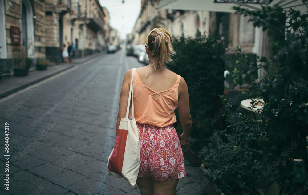 Naklejka premium Rear view of travel woman on a street walk