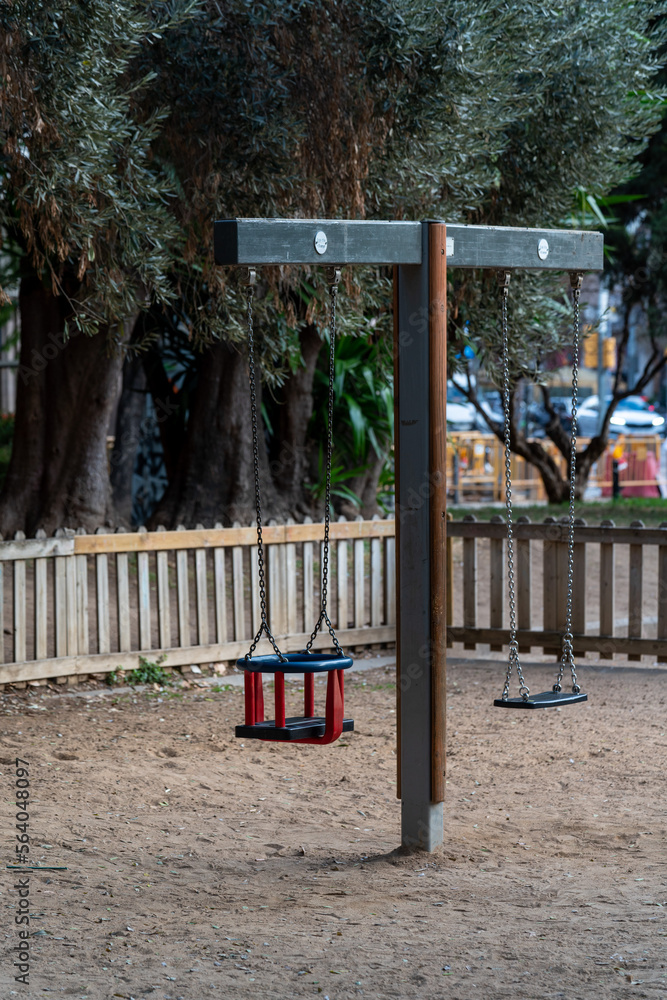 Empty wooden swing in outdoor playground for children in the park, Barcelona, Spain.