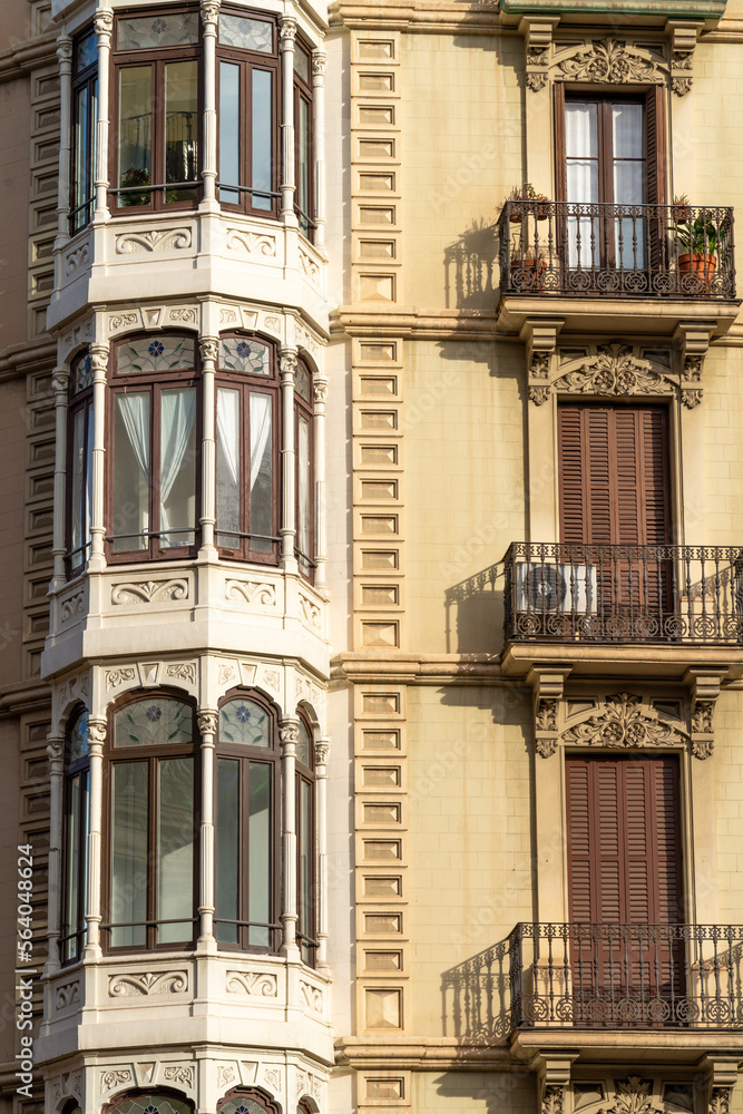 view of the facade of the building in the city of barcelona, windows with closed wooden shutters, art nouveau balconies.