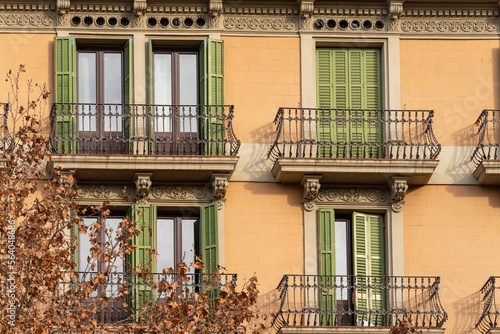 Traditional Barcelona style balconies and green wooden shuttered windows on facade of the renovated house on a sunny day, in the old city of the center Fototapet