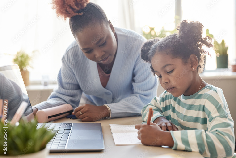 Black young teacher tutoring little girl studying at home Black young teacher tutoring little girl studying at home