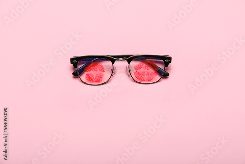 Eyeglasses with lipstick kiss marks on pink background