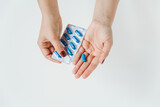 Women hands with blue pills blister. White background. Medical concept, flat lay, copy space
