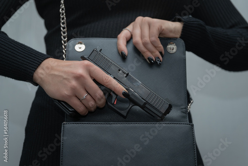 Firearms in women s hands  the girl takes out a gun from a handbag.