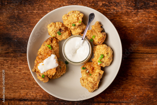 Cauliflower wings food. Pieces of flour-fried cauliflower with vegan sauces on a plate. Wooden background. Vegetarian food.