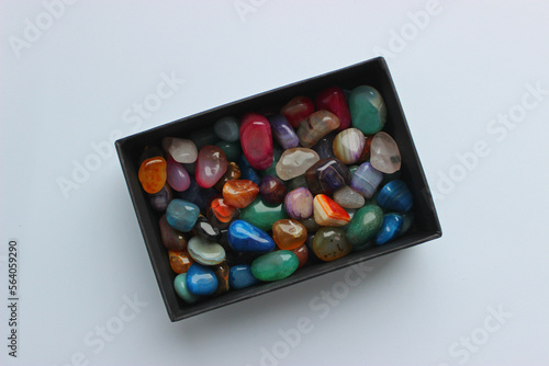 Bunch of raw semi-precious colored quartz stones in a black box top view 