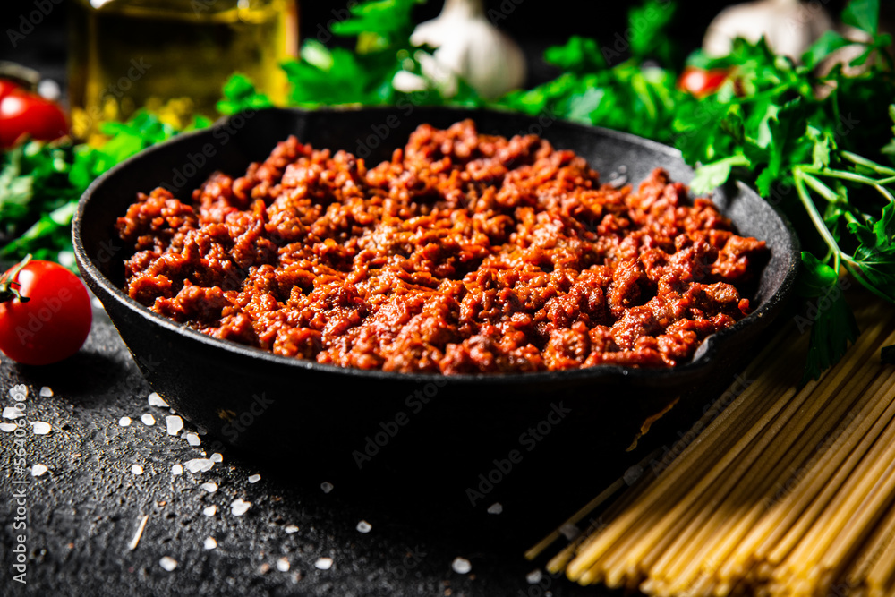 Bolognese sauce in a frying pan with pasta dry and parsley. Bolognese sauce in a frying pan with pasta dry and parsley.