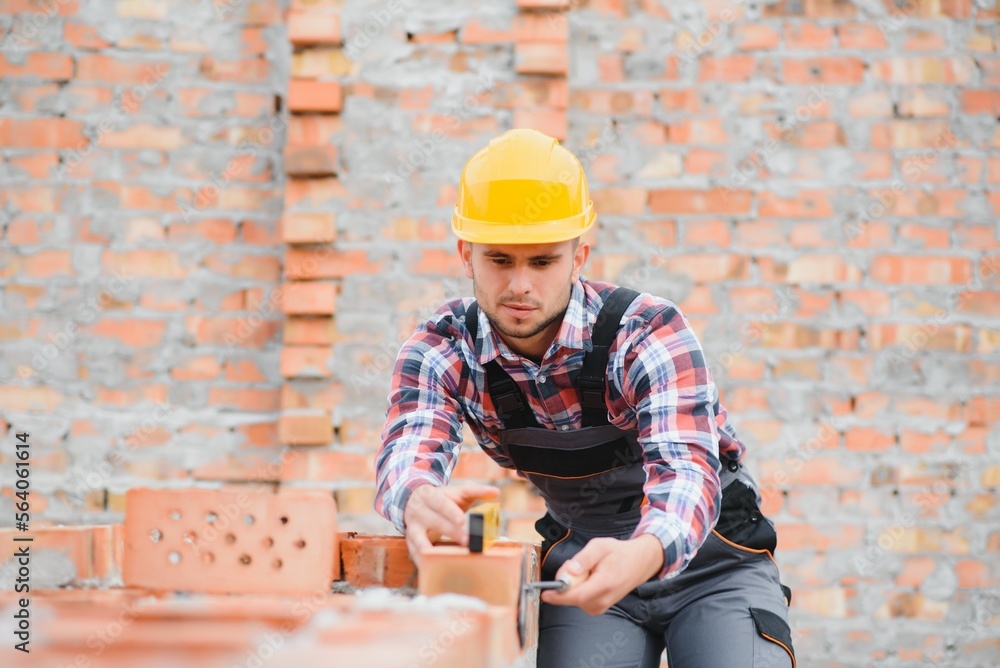 Construction worker man in work clothes and a construction helmet. Portrait of positive male builder in hardhat working at construction site. Construction worker man in work clothes and a construction helmet. Portrait of positive male builder in hardhat working at construction site.