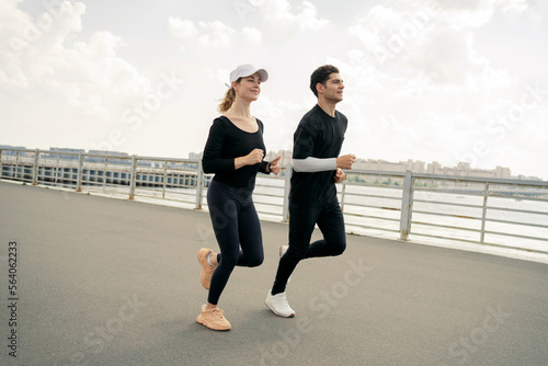 Jogging is a running track for a man and a woman leading a healthy lifestyle. Young beautiful athletic couple runners in fitness clothes and sneakers.