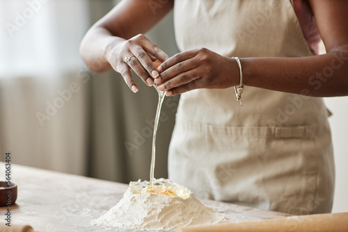 Black woman baking in kitchen and breaking eggs making homemade pastry © Seventyfour