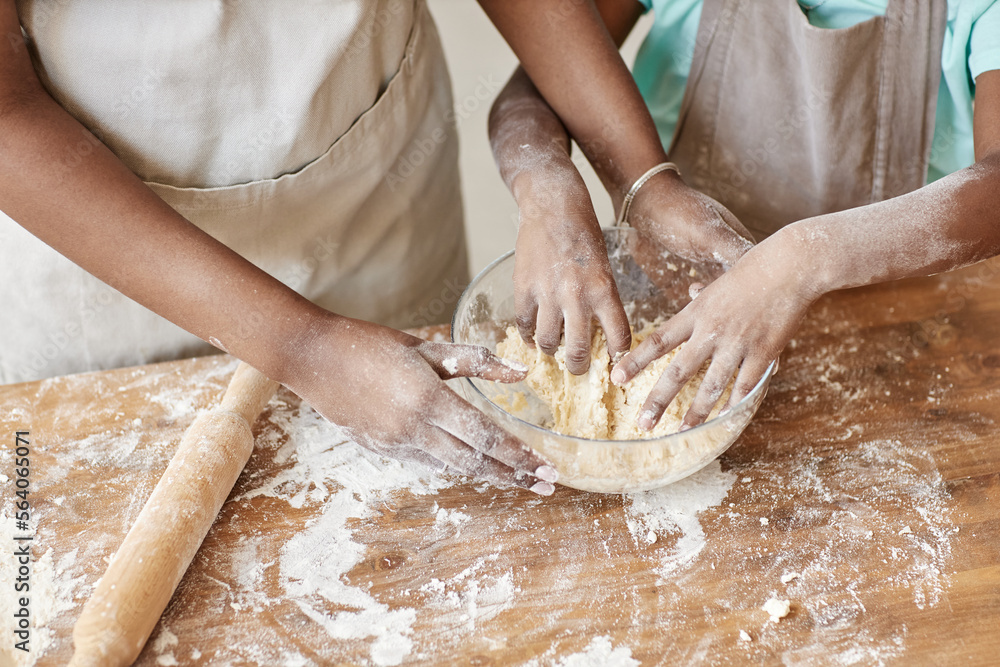 Mother and daughter kneading dough together baking homemade pastry