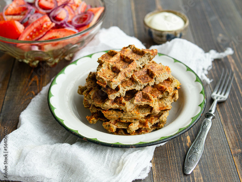Delicious eggplant wafflese in retro metal plate with tomato and onion salad and sauce ion wood background. Healthy vegeterian food. Close up, copy space.