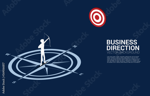 Businessman in suit shoot the arrow to target standing at center of compass on floor.Concept of career path and business direction.