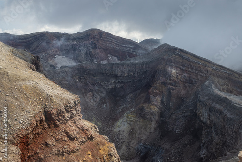 Severe mountain landscape. View of the top of the volcano. Rocks on the rim of a volcanic crater. Travel, tourism and hiking on the Kamchatka Peninsula. Gorely volcano, Kamchatka Territory, Russia.