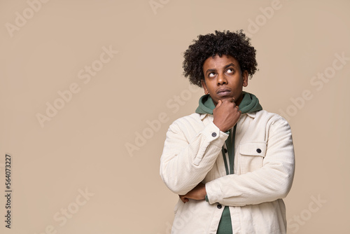 Konstfotografi Young thoughtful confused African American guy student thinking holding hand on chin, looking up, choosing, making decision, feeling doubt, having question isolated on beige background